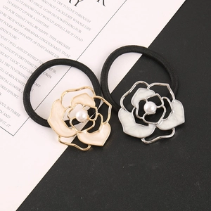 Close-up of camellia hair ties with alloy petals and pearls on a minimalist background