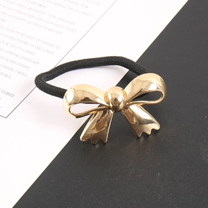 Detail of high-elastic black ponytail holder with a polished gold metallic bow charm