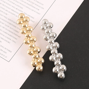 Detailed view of two metallic beaded hair clips in gold and silver finish with high polish