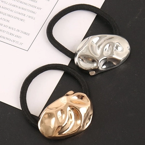 Detail of gold and silver ponytail holders with irregular lava texture metal charms