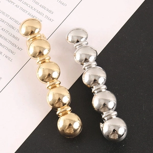 Détail de barrettes à perles métalliques dorées et argentées au fini brillant miroir