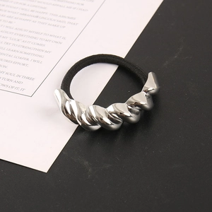 Minimalistisches schwarzes Haargummi mit silberner Metallspirale auf geteiltem Hintergrund