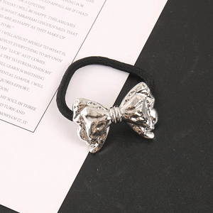Close-up of silver metal bow hair tie with textured finish on black elastic band