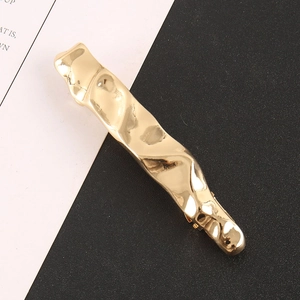 Detailed view of the irregular molten texture on a golden alloy hair clip for women