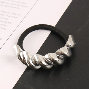 Detailansicht eines silbernen Metallornaments an einem elastischen schwarzen Haargummi