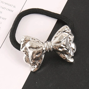 Close-up of silver bow hair ring with hammered texture and black elastic band detail