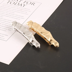 Detail view of wavy gold and silver metal hair clips with a polished alloy finish