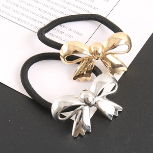 Detail of elegant gold and silver metal bow hair ties with elastic black bands