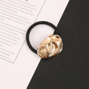 Detail of elastic hair tie with textured gold metal block on a magazine background