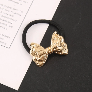 Detail of high-elasticity hair tie with a textured gold metallic bow for punk hairstyles