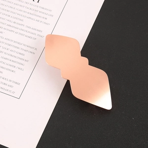 Vue macro détaillée d'une barrette géométrique en métal or rose avec une texture brossée mate