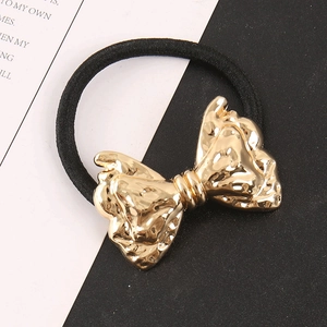 Hip hop style gold bow metal hair tie with textured hammer finish on a black elastic band