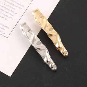 Close-up of wavy metal hair clips in gold and silver finish with polished texture