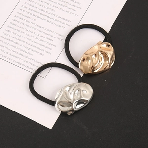 Macro detail of elastic hair ties with textured gold and silver oval metal charms