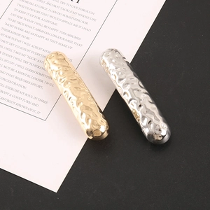 Detail of minimalist hair clips with hammered texture in gold and silver finish