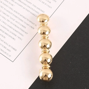 Barrette à cheveux minimaliste en métal doré au design sphérique sur fond noir et blanc