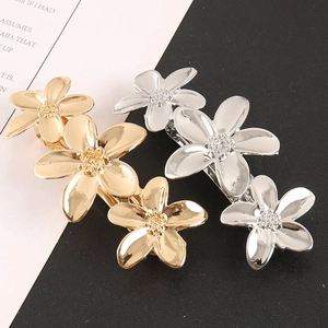 Détail de pinces à cheveux florales dorées et argentées avec trois fleurs liées