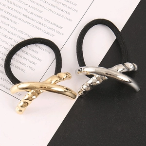 Detail view of crossed gold and silver metal buckles on elastic hair ties with hammered texture