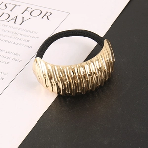 Macro detail of gold wavy-textured metal ornament on a black elastic ponytail hair tie