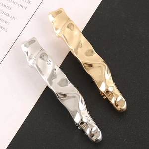 Detail of liquid metal hair clips in gold and silver with wavy textured finish