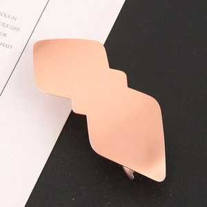 Détail d'une pince à cheveux géométrique en métal or rose avec une finition mate