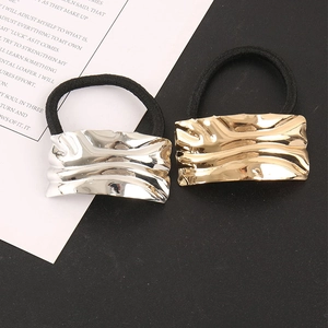 Detail of rectangular corrugated alloy hair tie showing golden and silver metal textures