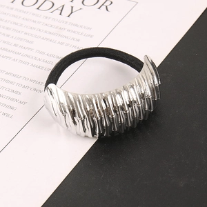 Close-up of elastic hair tie featuring large silver metal piece with textured surface