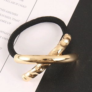 Detailed macro shot of a geometric gold metal charm on a black minimalist hair tie elastic