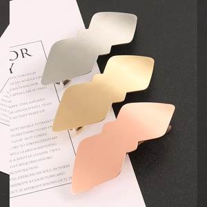 Trois barrettes géométriques en argent, or et or rose sur une carte décorative