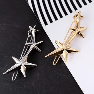 Detail of three-star hair clips in gold and silver finish with high-gloss metallic shine