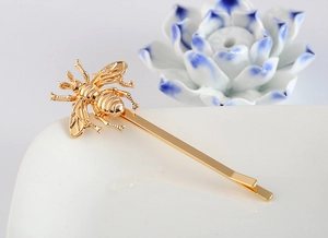 Detailed close-up of a golden bee hair clip with intricate wing textures on ceramic