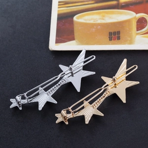 Minimalist gold and silver star hair clips with polished metallic finish on dark background