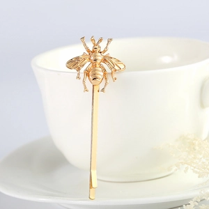 Elegant golden bee hair clip on a white ceramic cup with a minimalist aesthetic design