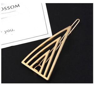 Detailed view of golden geometric triangle hair clip on a black textured background