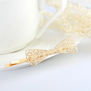 Detail shot of a golden lace hollow bow hairpin on a white porcelain plate
