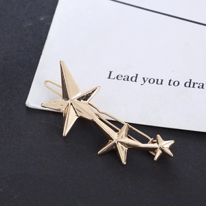 Detailed macro view of three golden alloy star hair pins on a branded display card