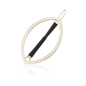 Detailed macro view of leaf-shaped hair clip with gold metal frame and black leather inlay