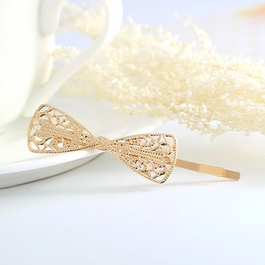 Detailed macro view of a gold hollow-out lace bow hairpin made of elegant alloy material