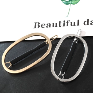 Détail de barrettes ovales en or et argent avec des accents noirs mats modernes