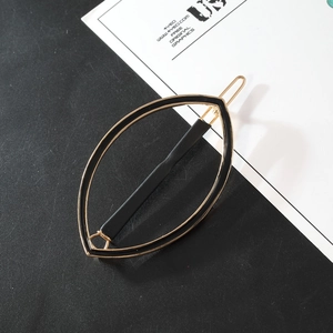 Detailed view of a black and gold marquise hollow leaf hair clip on a minimalist background