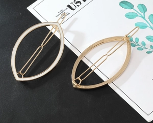 Detailed macro view of gold alloy leaf hair clips set with white enamel finish