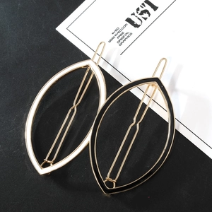 Detail of leaf-shaped hair clips in black and white enamel with gold-tone frames