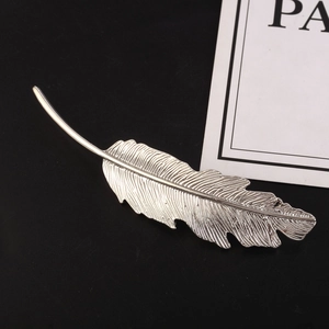 Macro shot of a silver feather hair clip with detailed metallic texture on black background