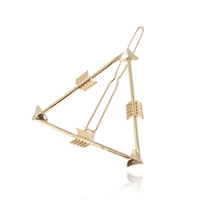 Detailed view of a gold triangular hair clip featuring arrow motifs and a polished surface