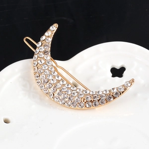Eleganter goldener Mond Haarclip mit funkelnden Strasssteinen auf dekorativem Keramikteller