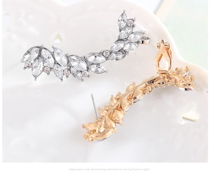 Dettaglio di orecchini a foglia marquise oro e argento su un piatto in ceramica