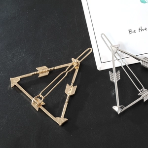 Macro detail of geometric hollow triangle hair clips in gold and silver finish