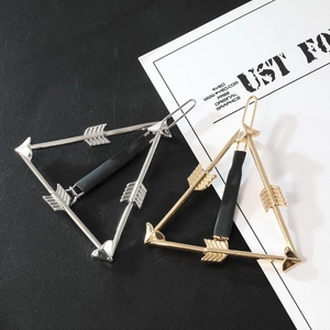 Detail of minimalist gold and silver arrow-shaped triangle hair clips on a modern background
