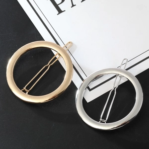 Macro detail of high-polish gold and silver round metal hair clips on a contrast background