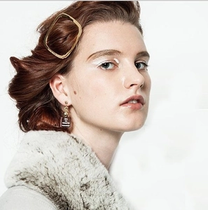 Pince à cheveux dorée et boucles d'oreilles flacon de parfum sur un mannequin